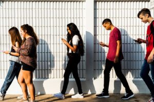 Group of young teenager friends walking home after school using